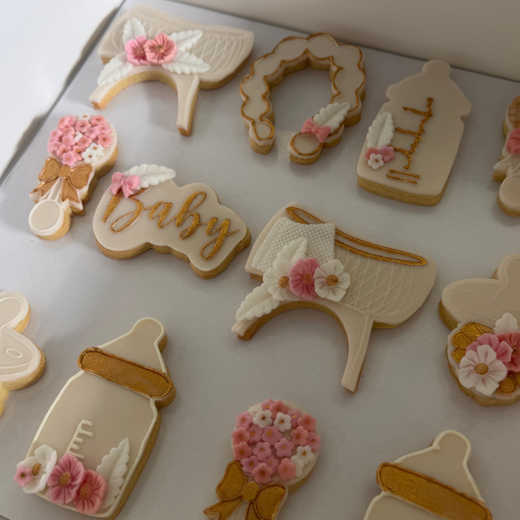 Decorative cookies shaped like baby items on a white box.