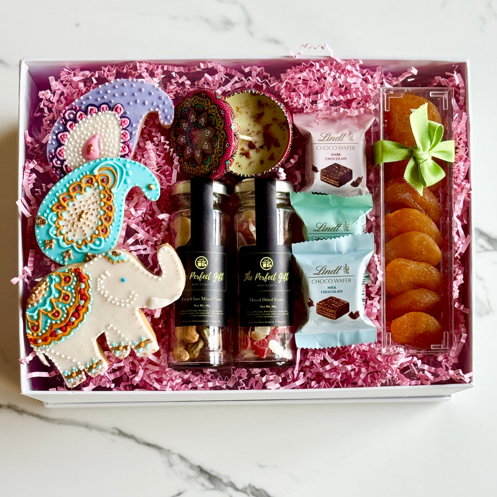 Gift box with decorative items and snacks on a marble surface