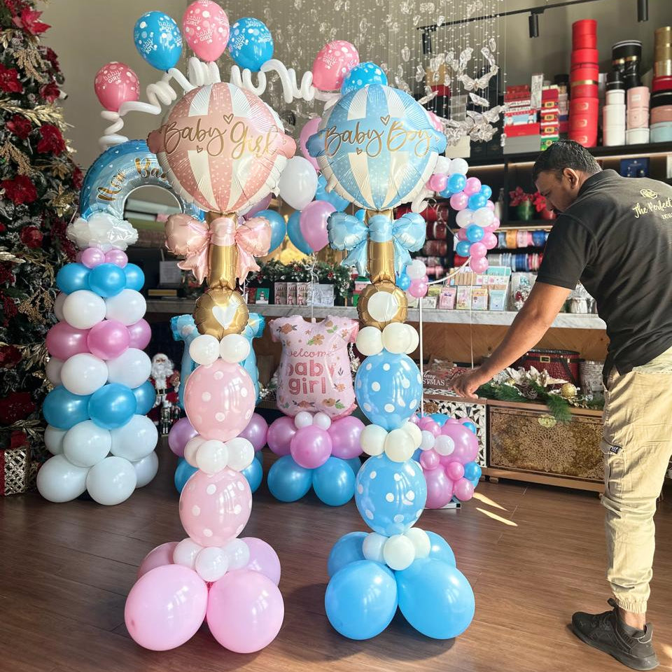 Colorful balloon arch with 'Baby Girl' text in a store setting.