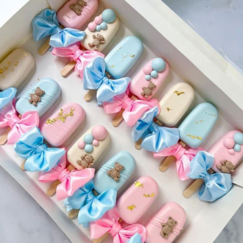 Pastel-colored ice cream popsicles with decorative bows and teddy bear figures on a white tray.