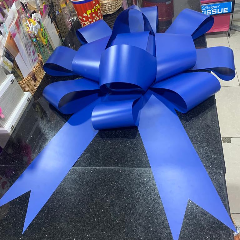 Large blue bow on a black surface with a store interior background