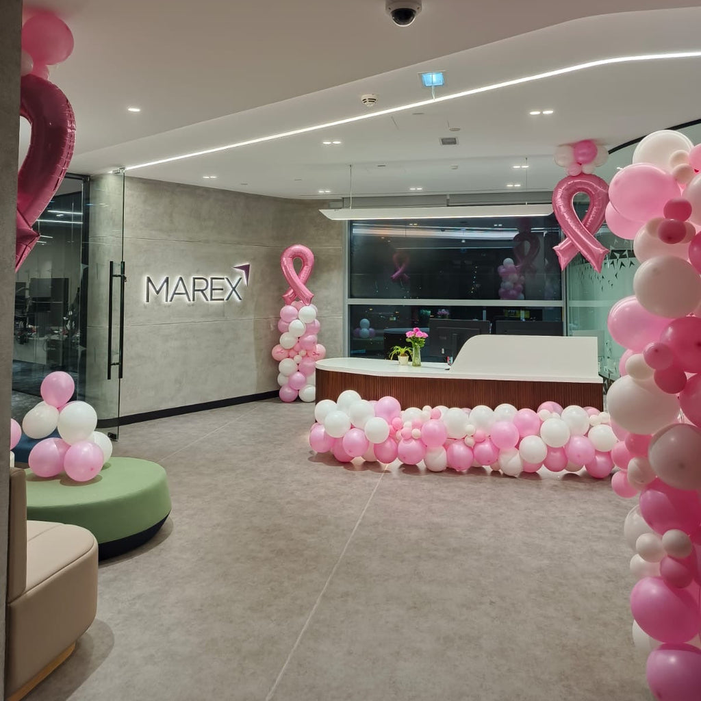 Decorated room with pink and white balloons, MAREX logo on the wall.