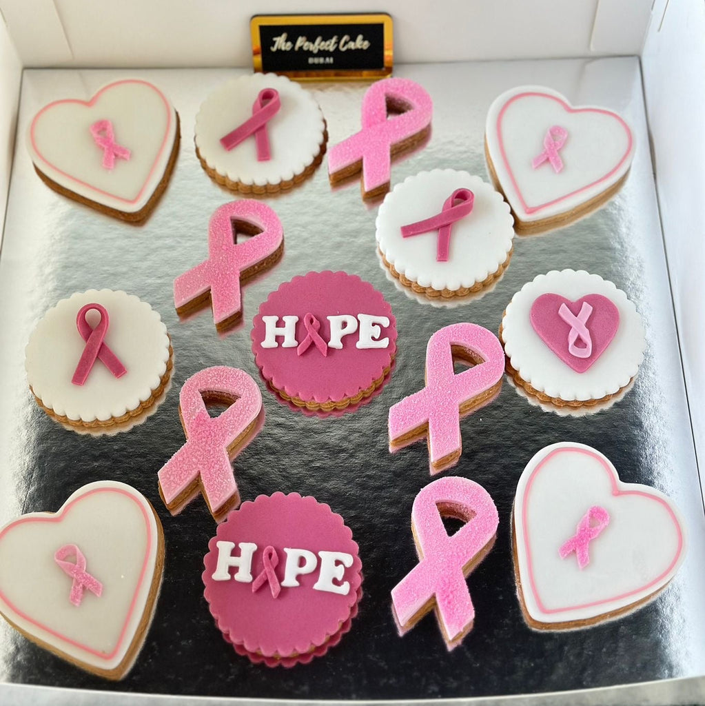 Decorative cookies with pink ribbons and 'Hope' text in a box, likely for breast cancer awareness.