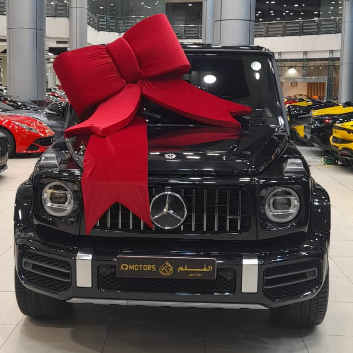 Black Mercedes-Benz car with a large red bow in a showroom.