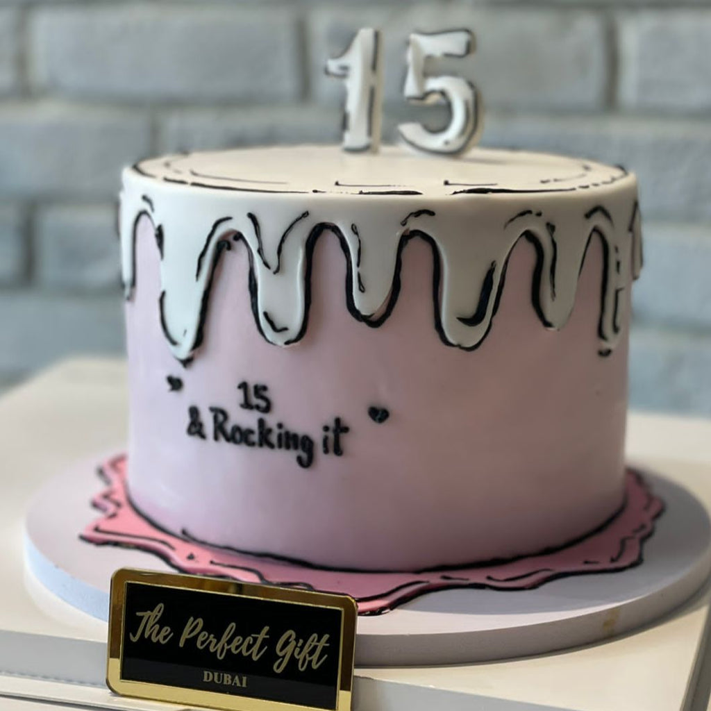 Pink cake with black decorations and number '15' on a gray surface.