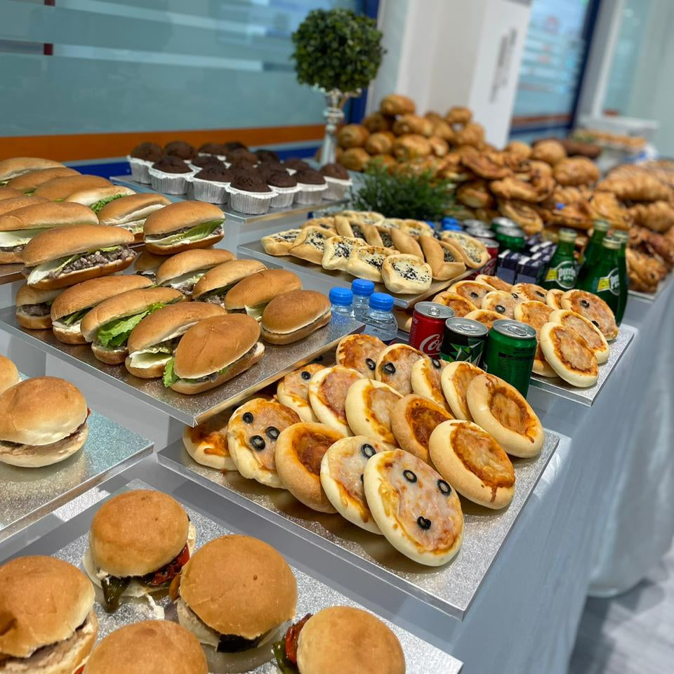 Display of various food items including sandwiches, pastries, and drinks in a buffet setting.