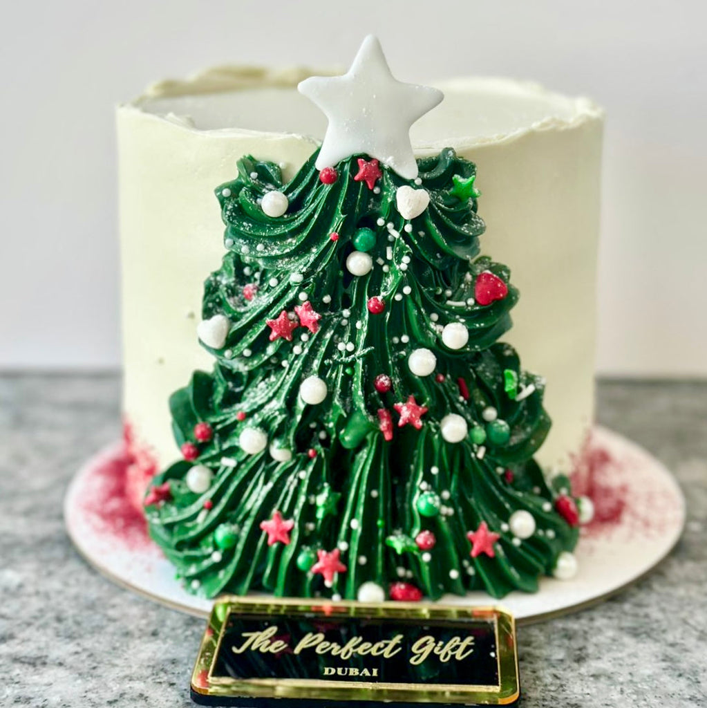 Christmas tree-shaped cake with decorative elements on a marble surface