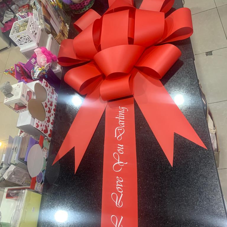 Large red gift bow with a ribbon on a dark surface