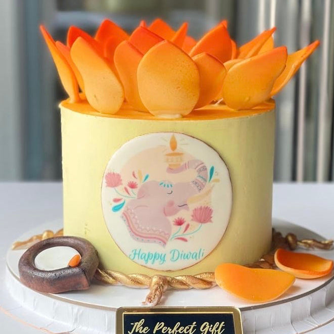 Decorative cake with orange flowers and a 'Happy Diwali' message on a white surface.