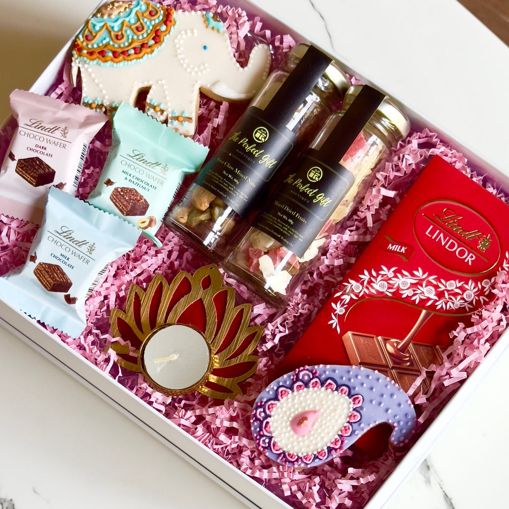 Gift box with Lindt chocolate, candles, and other items on a white surface