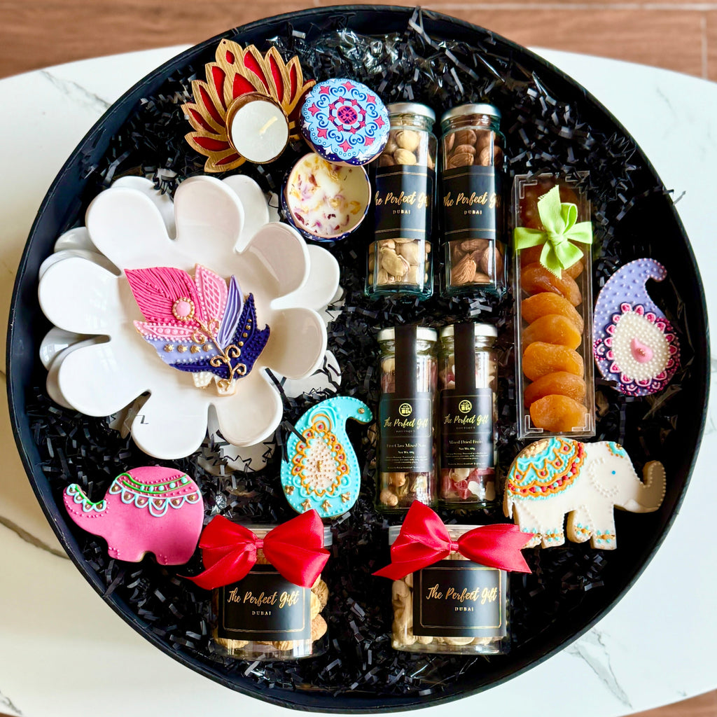 Decorative black tray with assorted snacks and candies on a white surface.