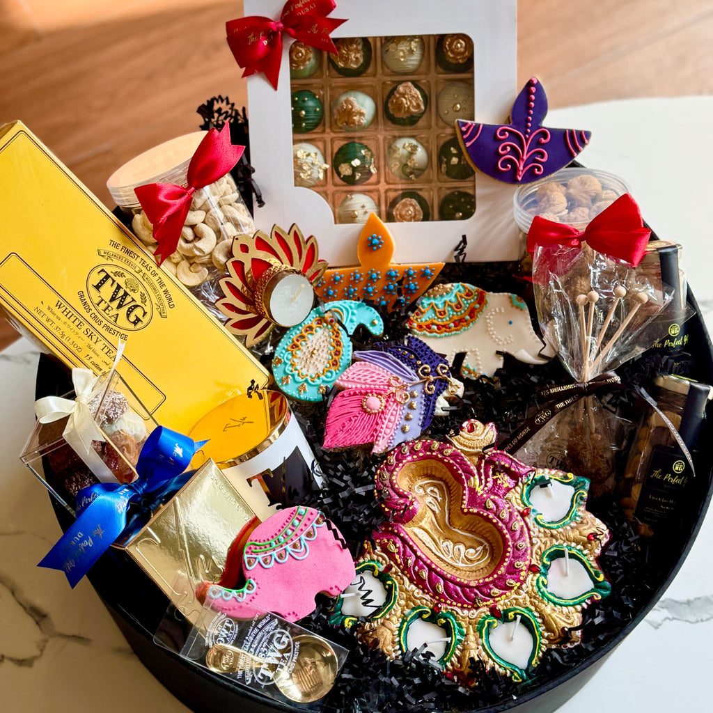 Decorative gift basket with colorful items including a box of chocolates, a TWG tea bag, and decorative items on a marble surface.