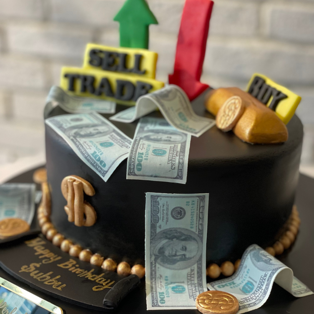 Cake decorated with money, arrows, and trading symbols on a black cake stand.