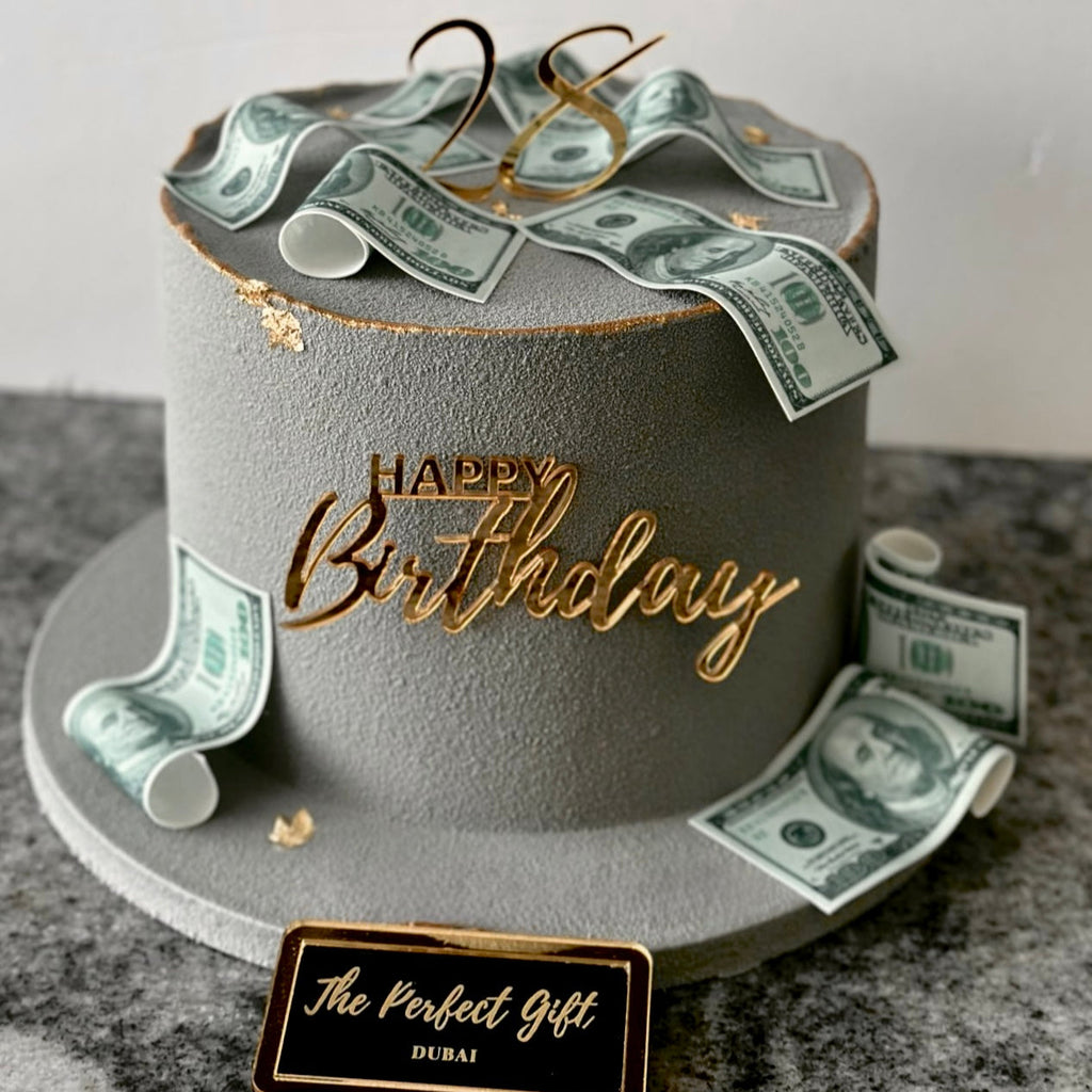 Birthday cake with dollar bills and 'Happy Birthday' decoration on a gray background
