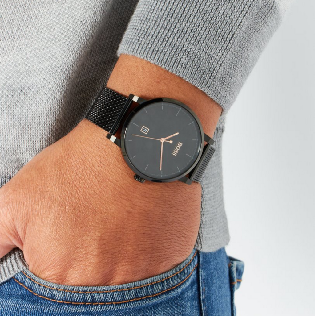 Person wearing a black watch on a plain background