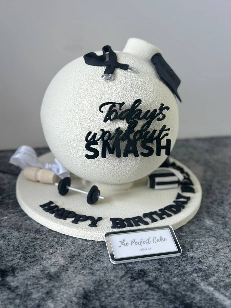 Birthday cake shaped like a tennis ball with 'Today's workout SMASH' text, surrounded by tennis-themed decorations.