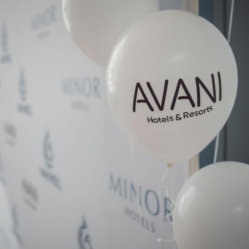 White balloons with 'AVANI Hotels & Resorts' logo in front of a branded backdrop.