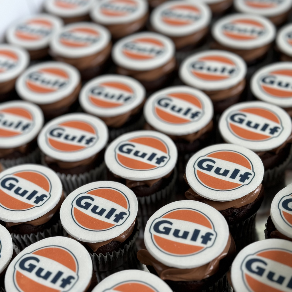 Chocolate cupcakes with Gulf logo on top arranged in rows.