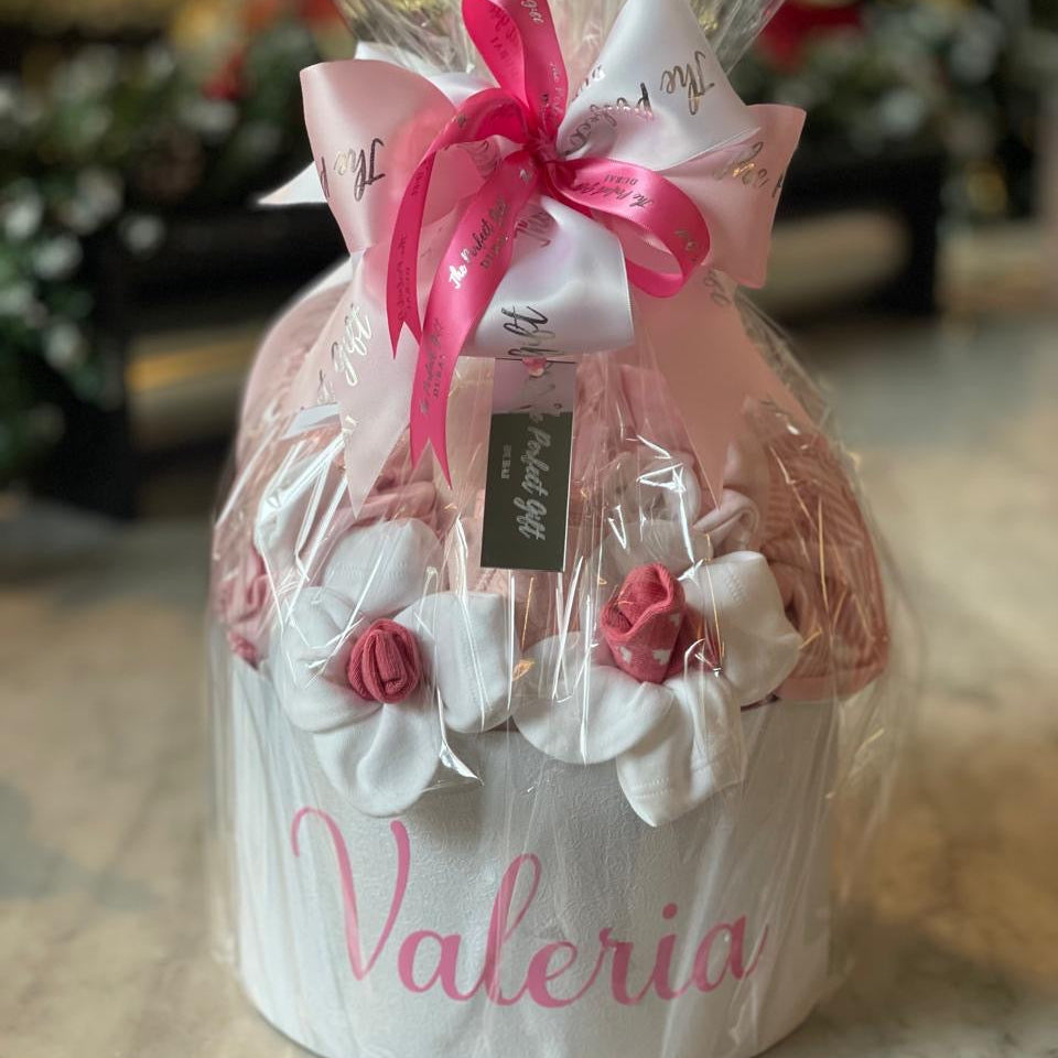Gift basket with pink flowers and 'Valeria' branding on a marble surface.