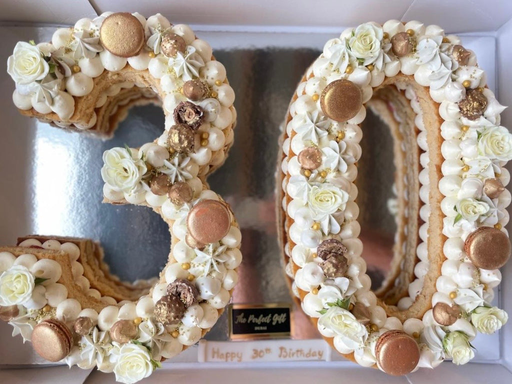Decorative numbers '30' made of flowers and macarons on a white background