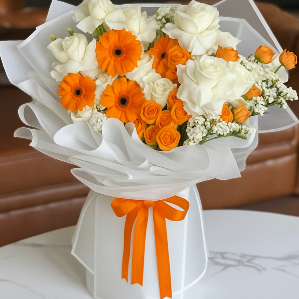 Bouquet of white and orange flowers with an orange ribbon on a marble surface.