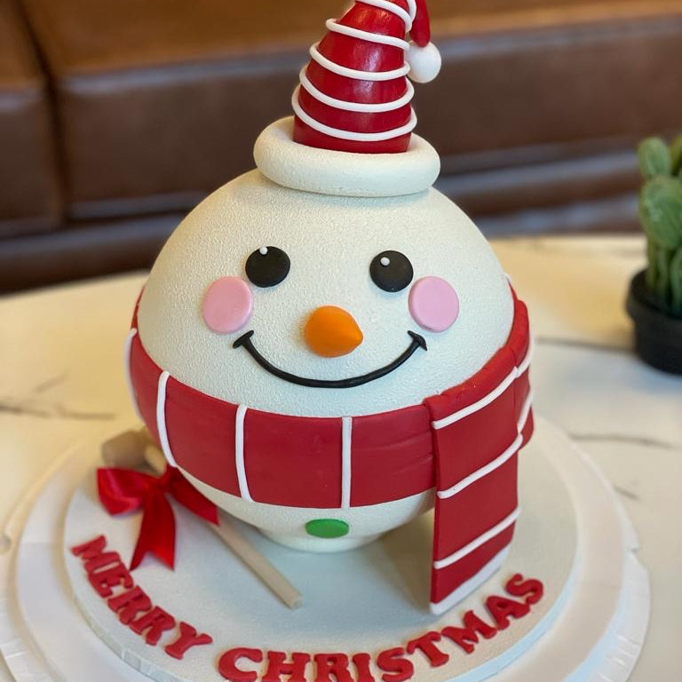 Christmas-themed cake with a snowman design on a white plate.