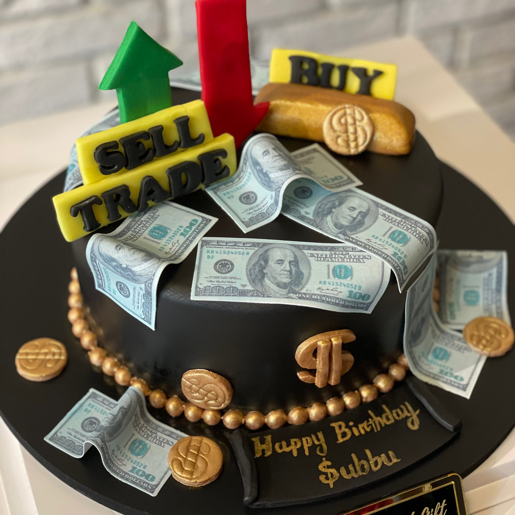 Cake with financial-themed decorations including money, arrows, and a sign on a gray brick wall background.